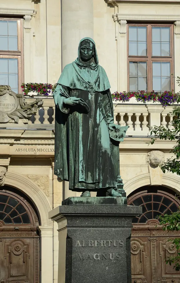 Bronze statue of Albert the Great in a Dominican habit holding a book, standing on a tall stone pedestal inscribed Albertus Magnus in front of the town hall of Lauingen