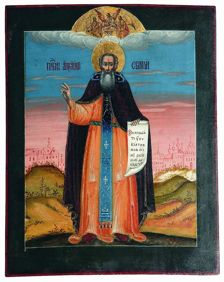 Russian icon of St. Alexander standing full length in a dark mantle and blue schema, holding an open scroll and blessing, with the Holy Trinity in the clouds above and a monastery in the landscape below