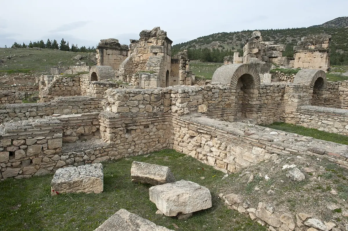 Stone walls and arched rooms of the ruined Martyrium of St. Philip on the hill above Hierapolis, with fallen blocks in the grass