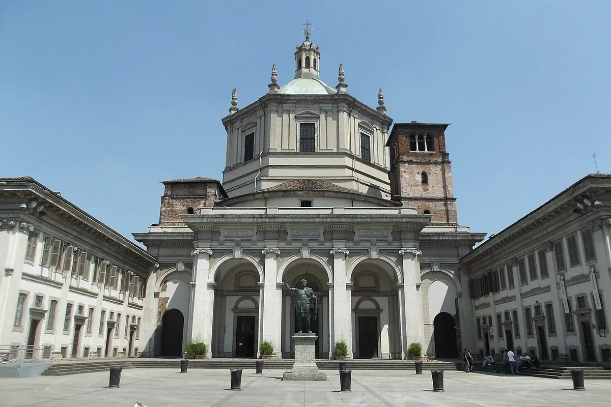 The front of the Basilica of San Lorenzo Maggiore in Milan with its white portico, great dome and a bronze statue of Emperor Constantine in the square