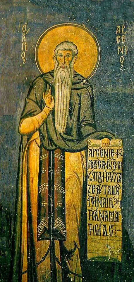 Byzantine fresco of a tall monk with a gold halo and a white beard reaching his knees, holding a long scroll covered in Greek writing