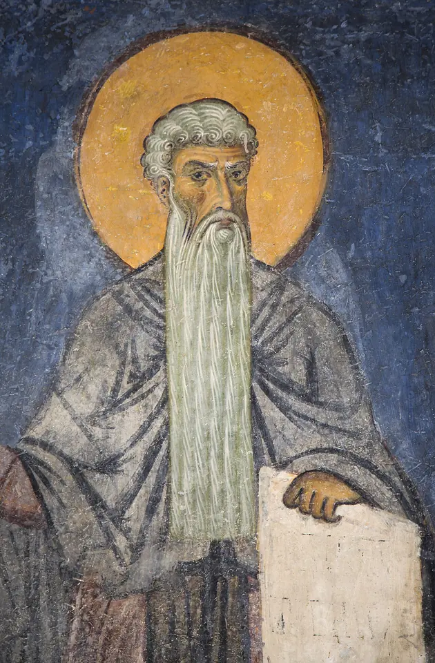 Close view of a Byzantine fresco of a gray-haired monk with a golden halo, a long silver beard and a grave face, his hand resting on a scroll