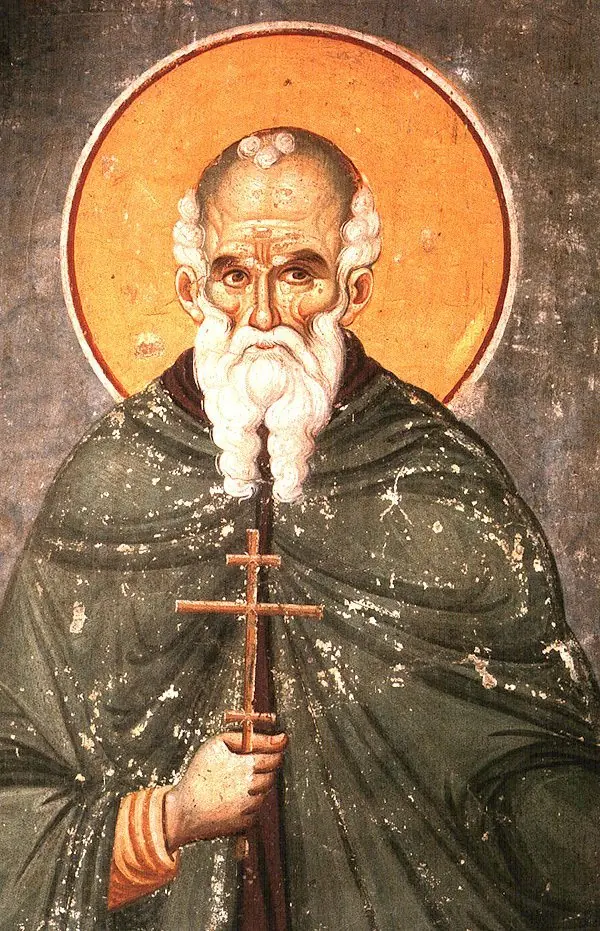 Byzantine fresco of an old monk with a high forehead, white hair and a long white beard, in a dark green mantle, holding a cross, against a gold halo