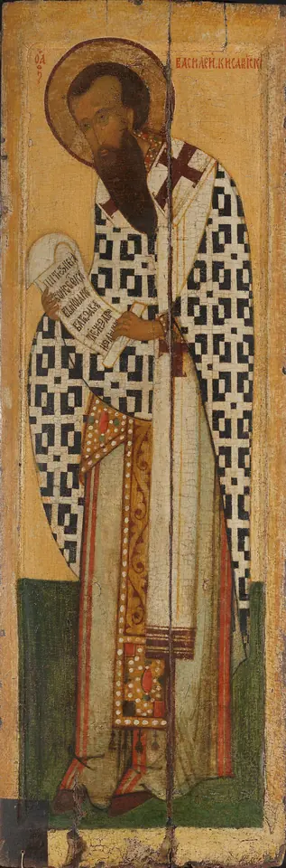 Tall Russian icon of St. Basil standing in a white omophorion with black crosses, holding a scroll and blessing, against a pale gold ground