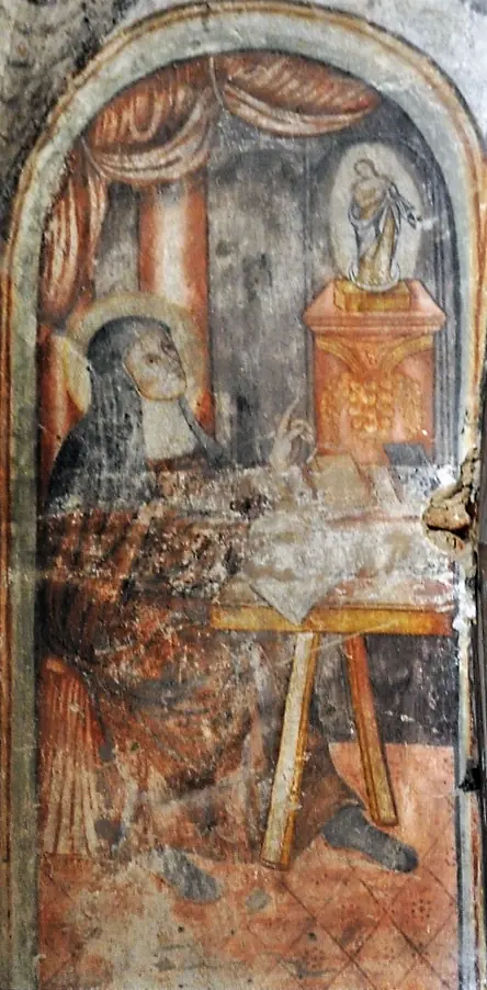 Faded wall painting of a veiled nun seated at a desk in prayer before a small image of the Virgin Mary