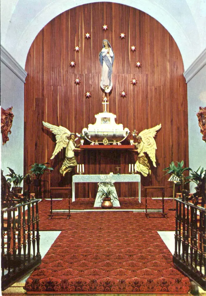 Chapel sanctuary with a statue of the Immaculate Virgin under a ring of stars above a white tomb flanked by two gilded angels