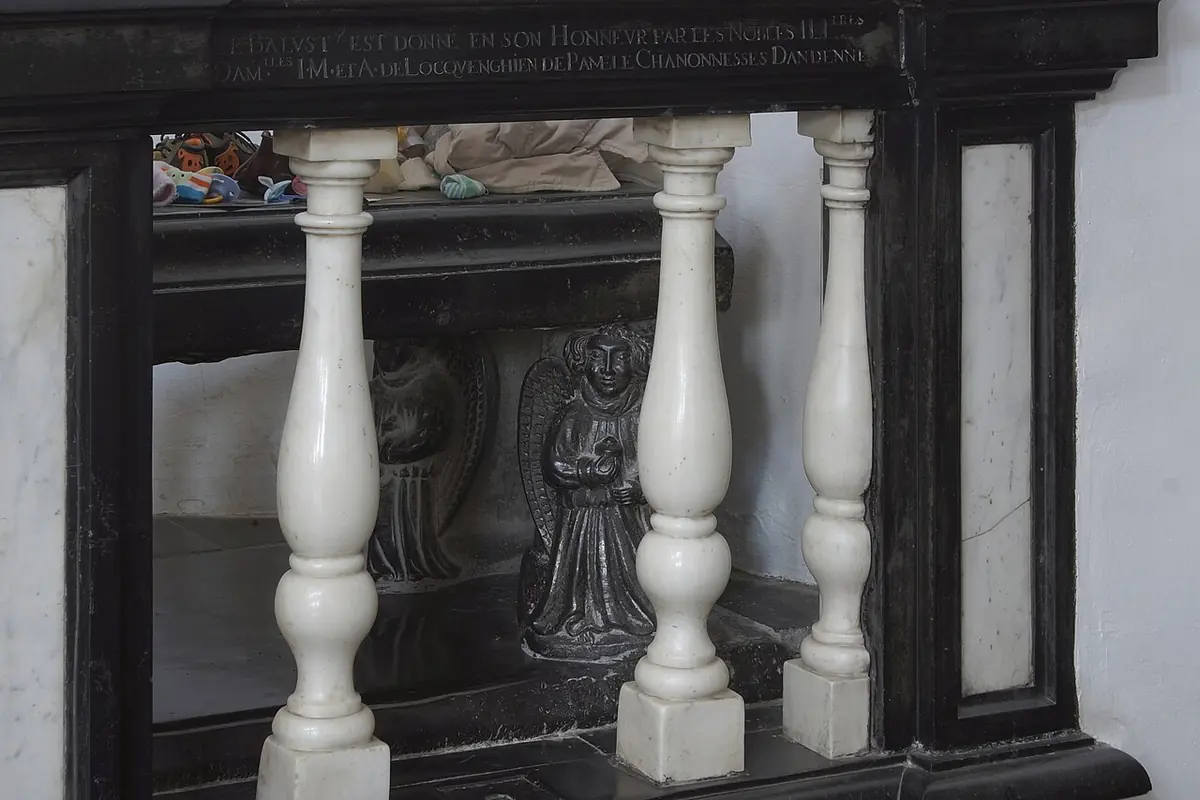 Black marble tomb with white marble balusters in a side chapel, with carved figures visible through the openings
