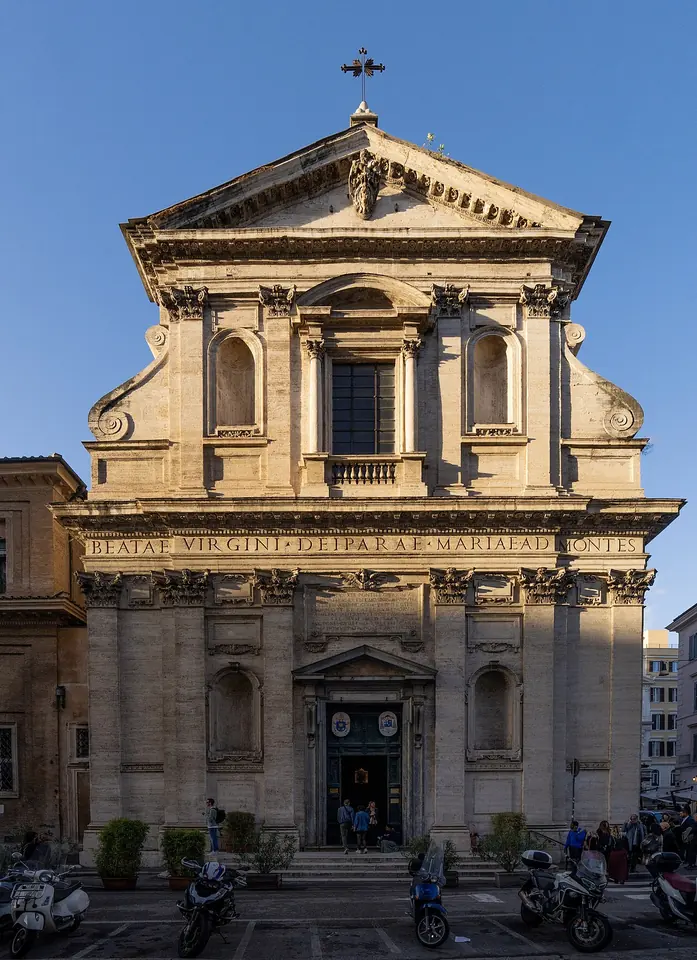 The tall travertine late-Renaissance facade of Santa Maria ai Monti in Rome, with its triangular pediment and a cross on top