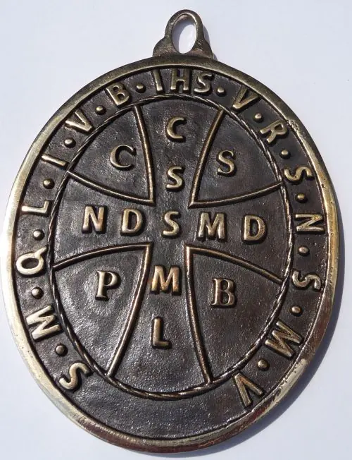 Back of the oval bronze medal, a cross lettered CSSML and NDSMD with C S P B in its corners, IHS at the top and the letters of the Vade retro prayer around the rim