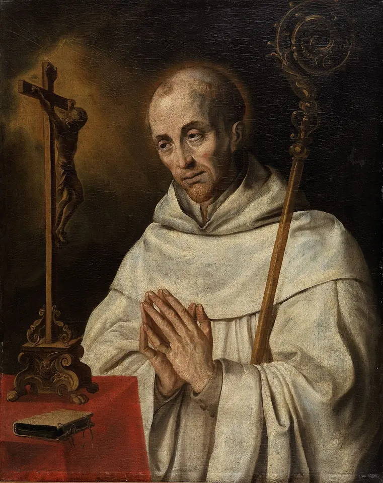 Half-length portrait of a tonsured monk in a white cowl with hands joined in prayer, an abbot's crozier at his shoulder and a crucifix and book on the table beside him