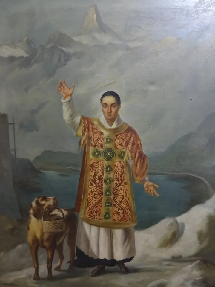 Painting of a young saint in a richly embroidered red dalmatic blessing, with a large St. Bernard dog carrying a small barrel beside him and a mountain lake behind