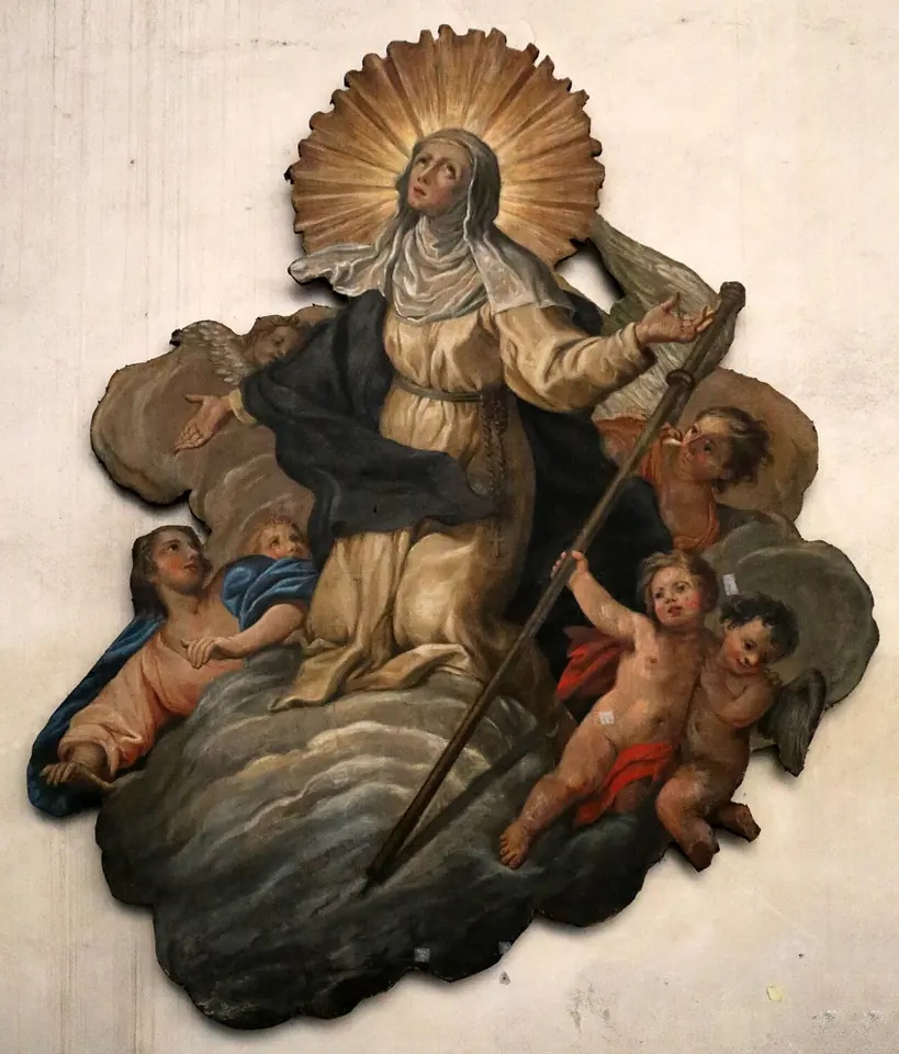 Painted relief of a woman in a dark habit and white veil kneeling on clouds with a pilgrim's staff, her head ringed with golden rays, surrounded by cherubs
