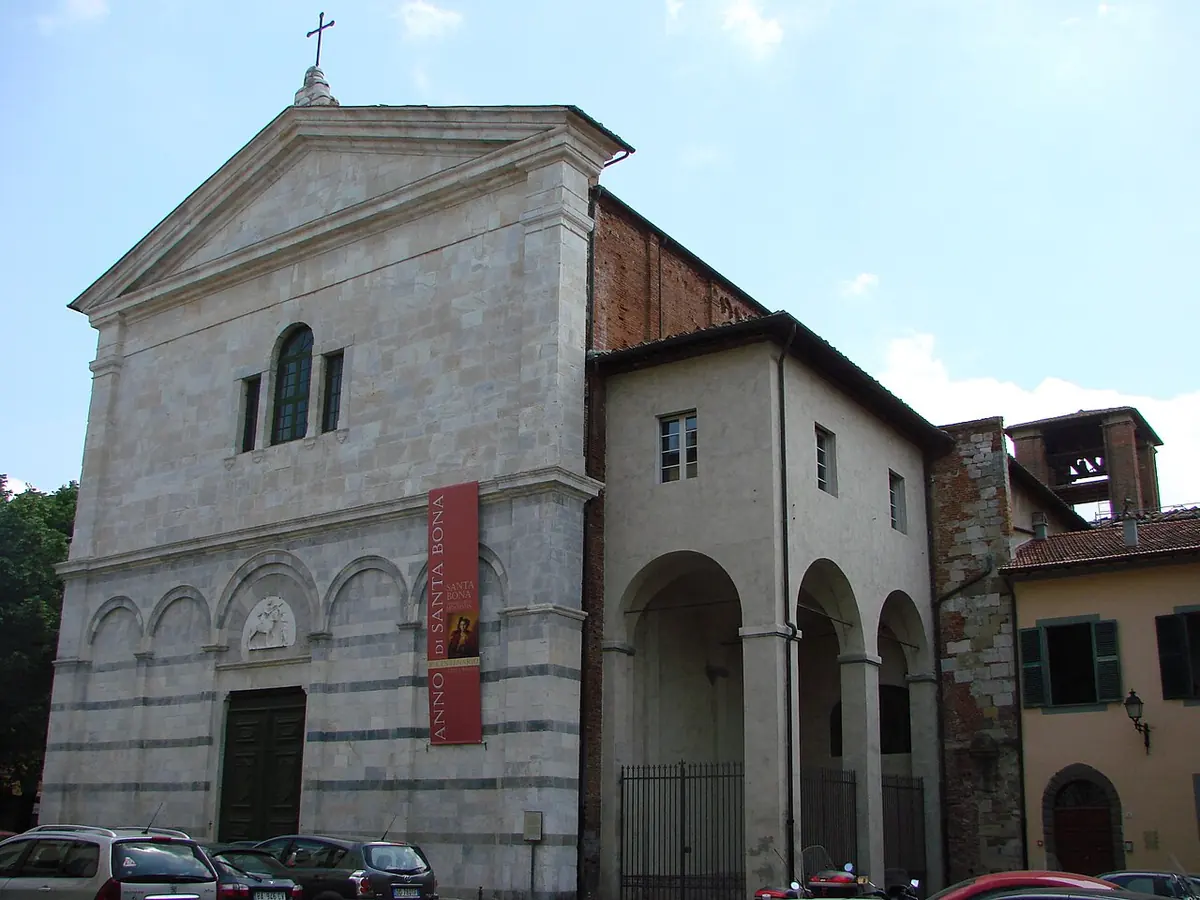 Romanesque church front of striped marble with blind arcades, a round window and a portico of arches on the right