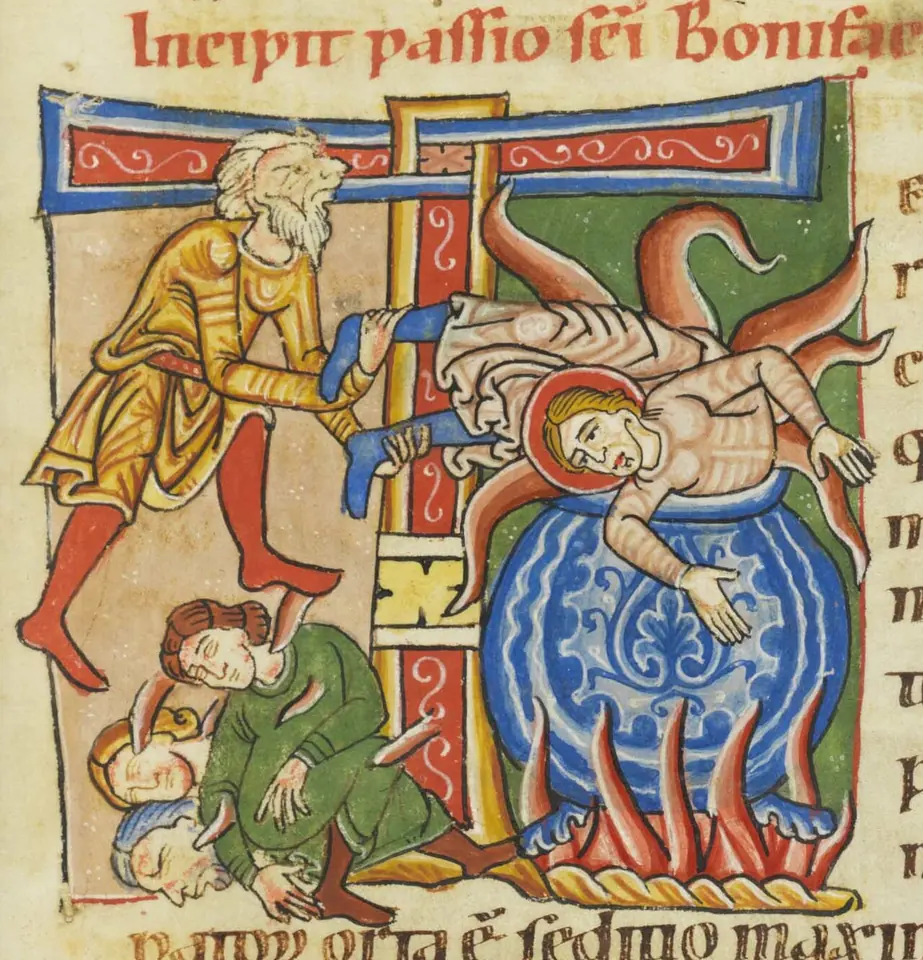 Medieval manuscript initial showing a haloed young man set head down into a blue cauldron over flames while executioners stoke the fire