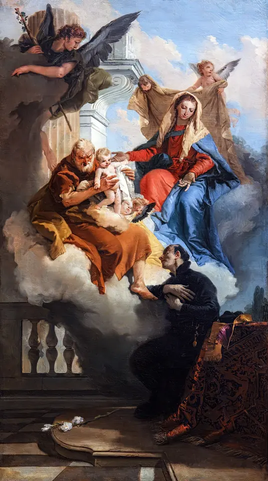 Retablo alto de Tiepolo con un sacerdote de negro arrodillado en una terraza, mientras la Virgen María de azul y San José le acercan al Niño Jesús desde una nube de ángeles