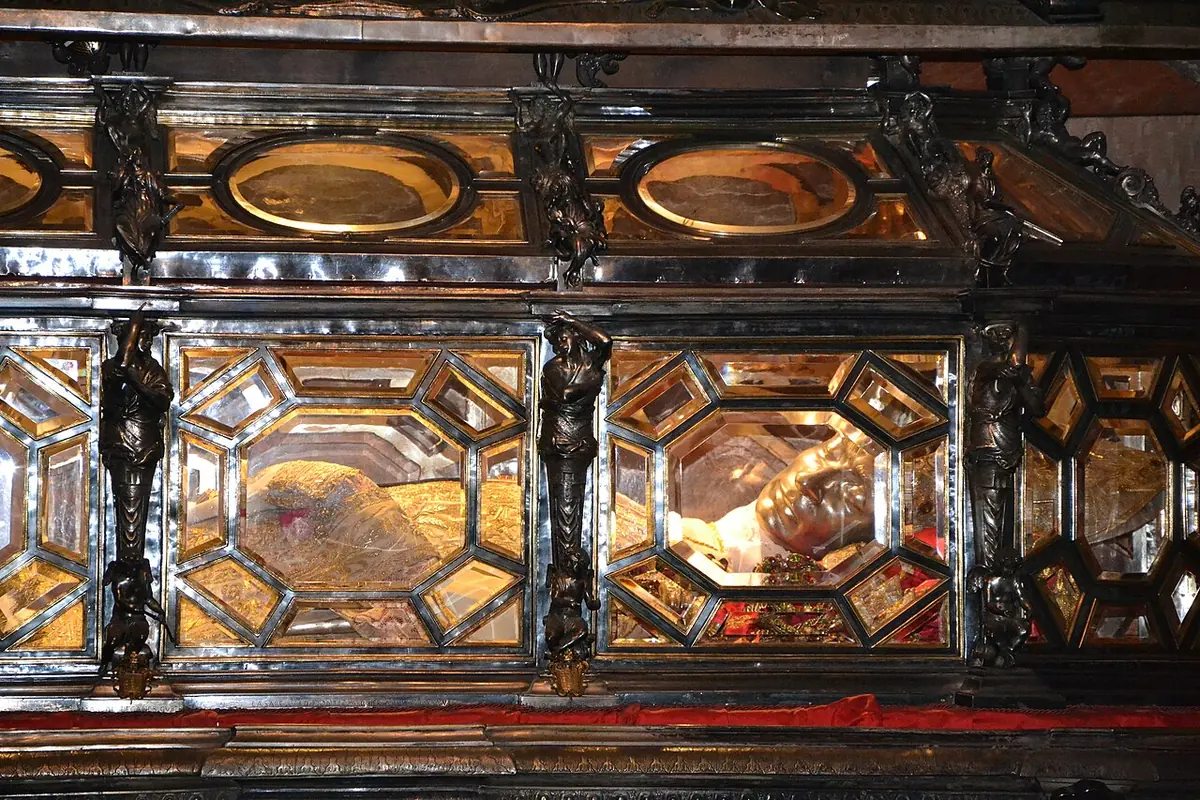 A small, dark octagonal crypt chapel with a silver altar and above it a silver and crystal urn, under a hanging candelabrum