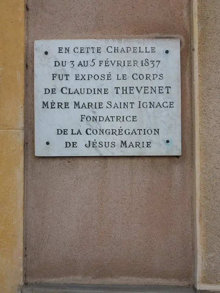 A marble plaque on a pink wall reading in French that in this chapel, from February 3 to 5, 1837, the body of Claudine Thévenet, Mother Mary of St. Ignatius, foundress of the Congregation of Jesus and Mary, lay in state