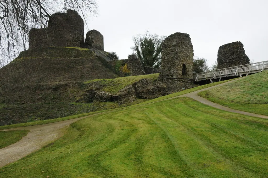The ruined round keep and towers of Launceston Castle on a grassy mound, with a wooden footbridge leading up to them