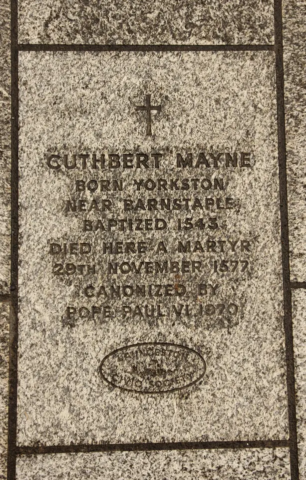 A granite memorial slab carved with a cross and the words Cuthbert Mayne, born Yorkston near Barnstaple, baptized 1543, died here a martyr 29th November 1577, canonized by Pope Paul VI 1970
