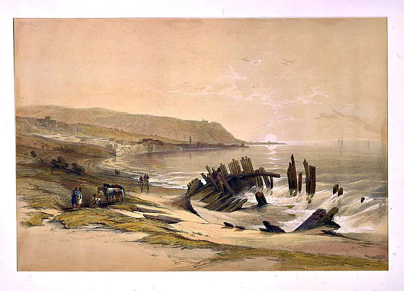 A pale lithograph of a wide bay with the wreck of a wooden ship in the surf, a town along the shore and the long ridge of Mount Carmel ending in a headland