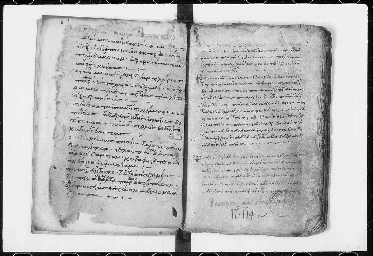 An open medieval manuscript in Greek, two worn pages of small dark handwriting with red initials, photographed in black and white