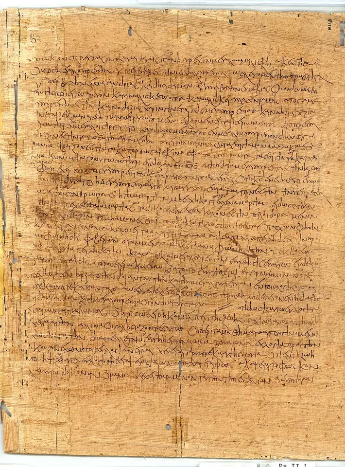 A tan papyrus page covered edge to edge in dense, faded Greek handwriting
