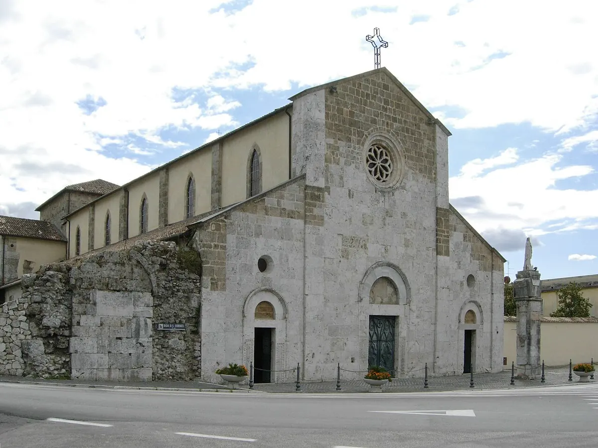 The pale stone Romanesque facade and long nave of the abbey church of San Domenico at Sora, with a rose window and a column in front