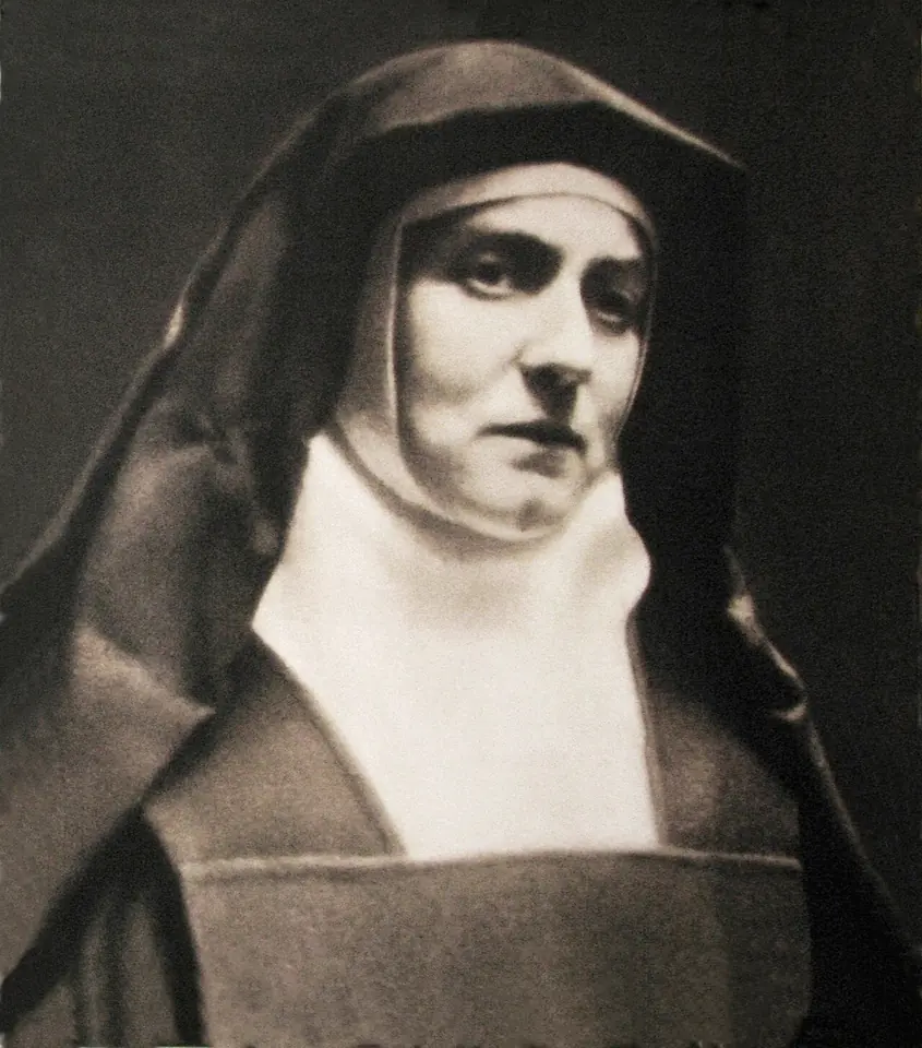 Sepia photograph of a Carmelite nun in a dark veil and white wimple, her face serious and tired
