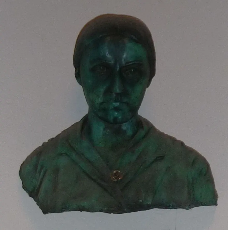Bronze bust of Edith Stein with short hair and a simple dress, mounted on a pale wall