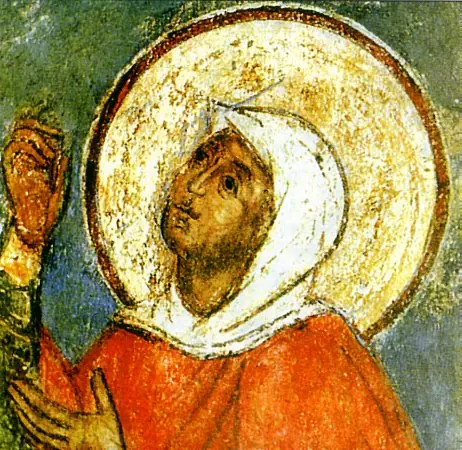 Detail of an old Orthodox fresco of St. Euphemia, her face turned upward under a white veil and gold halo, wearing a red cloak, one hand raised