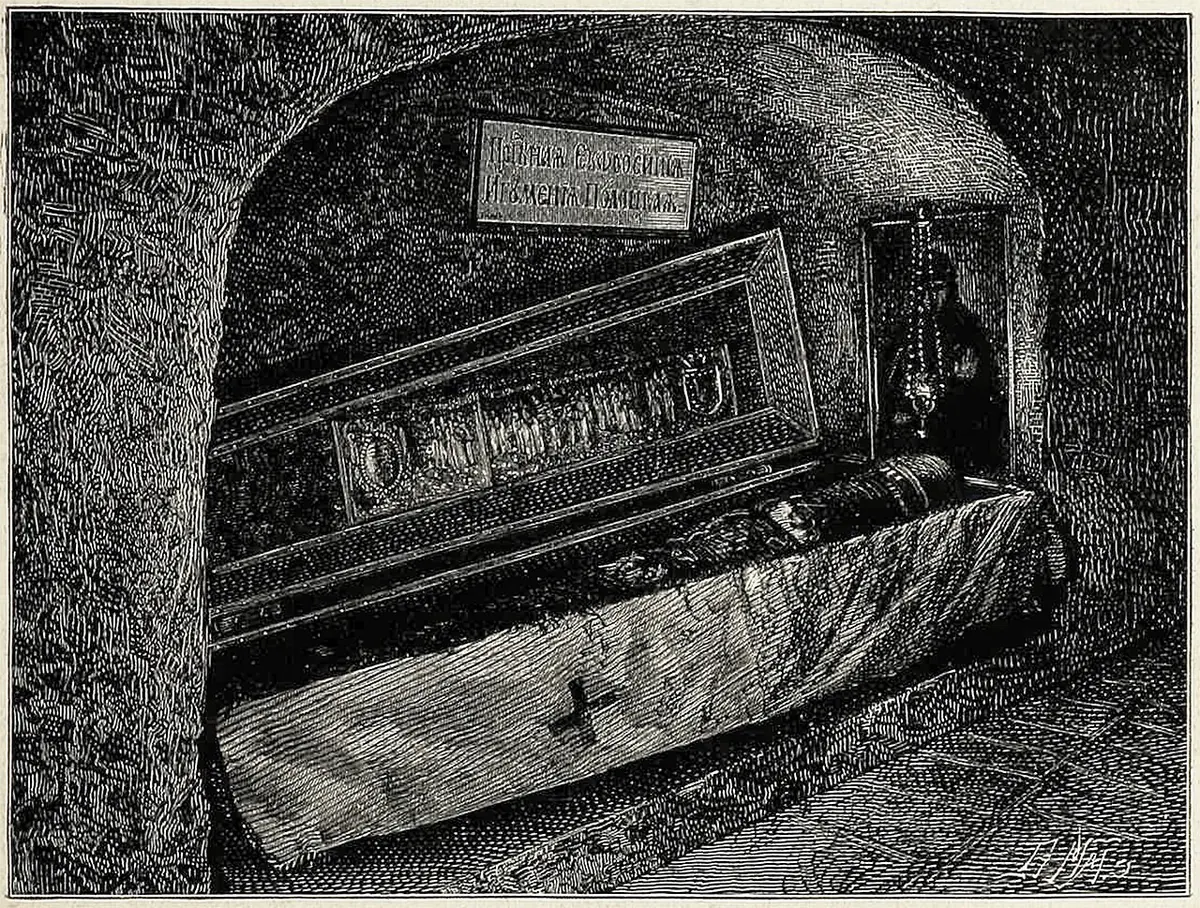 An old engraving of a low cave chapel with a long coffin-shaped shrine under a cloth marked with a cross, and an icon lamp hanging beside it