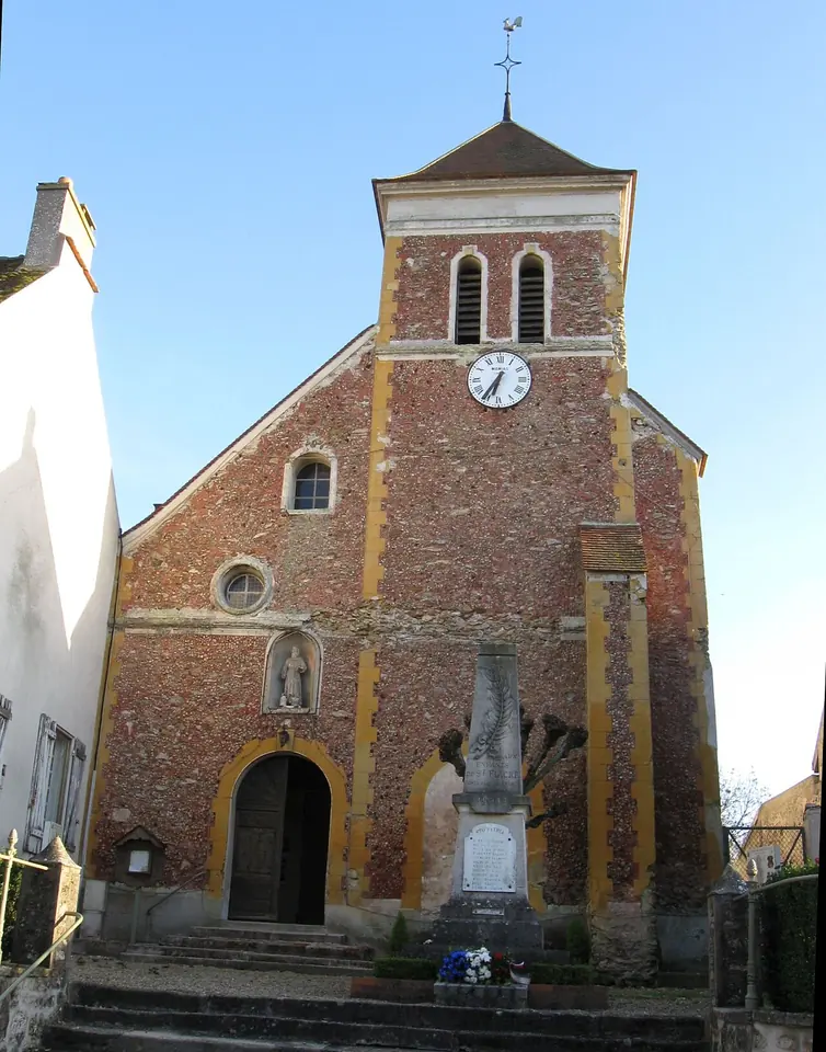 A small brick and stone village church with a square bell tower and clock, on the site of Fiacre's hermitage east of Meaux