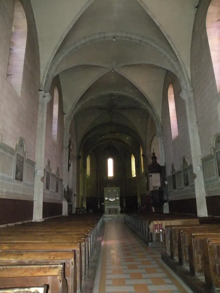 The long vaulted nave of the nineteenth-century church of Saint-Fraimbault at Lassay, with wooden pews leading to a bright choir