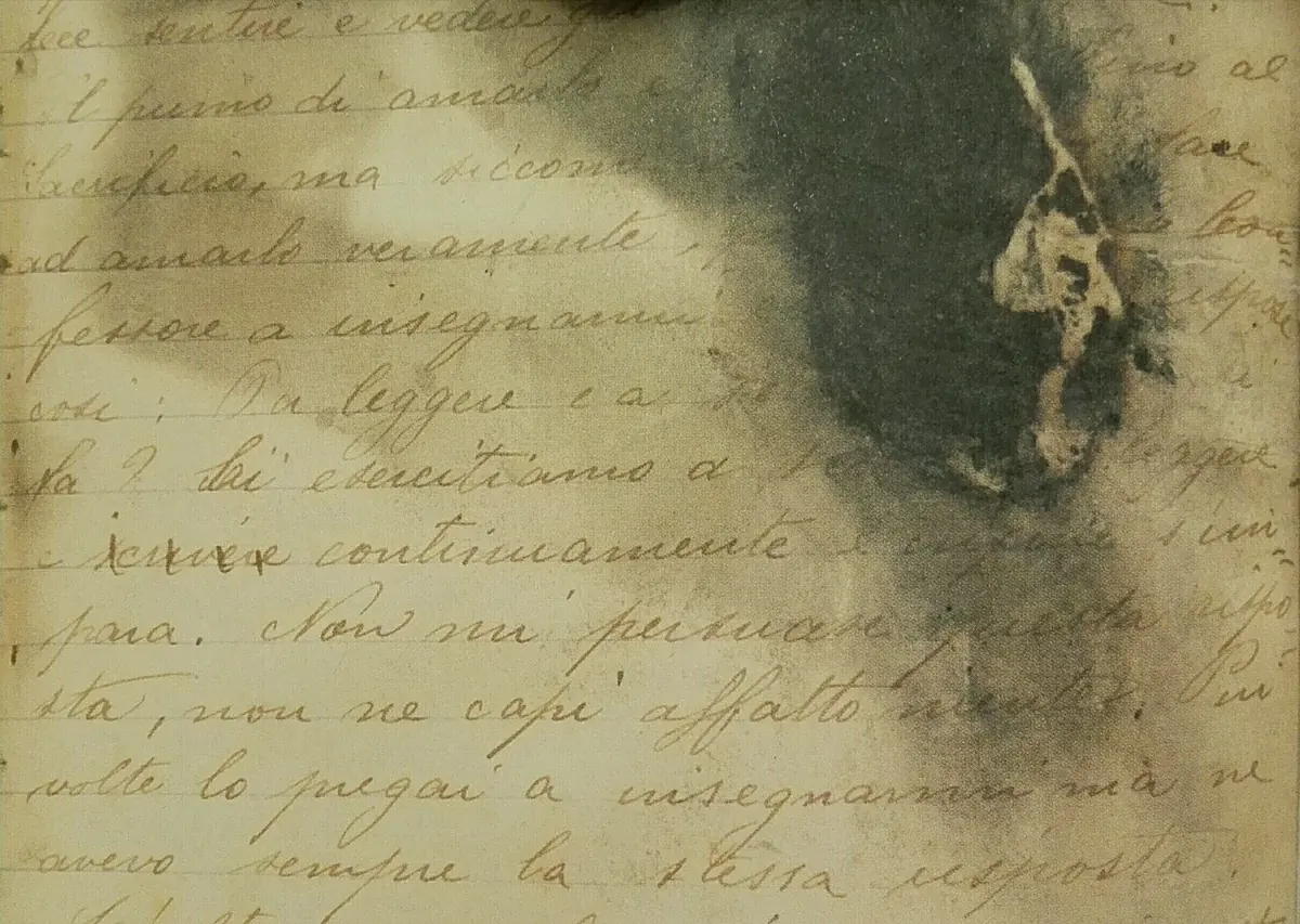 Close view of an old handwritten page in Italian, partly darkened by a large scorch mark