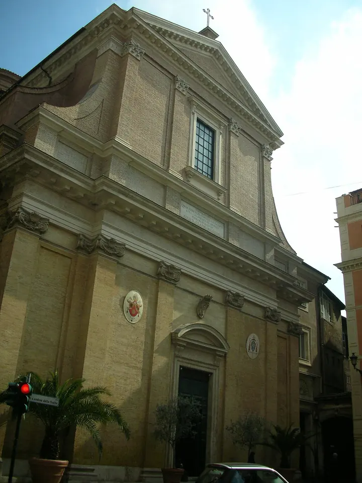 The tall ochre facade of the church of Sant'Andrea delle Fratte on a narrow Roman street