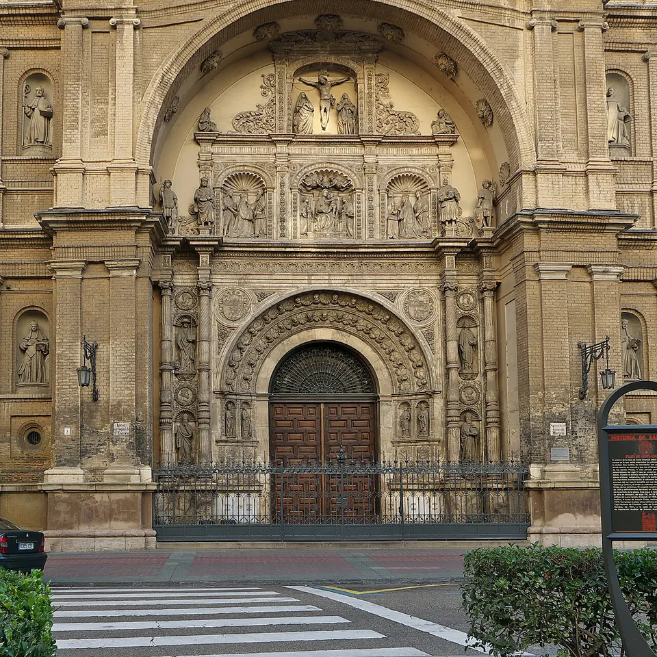 An ornate carved stone church portal with tiers of saints and a Crucifixion scene above a pair of dark wooden doors