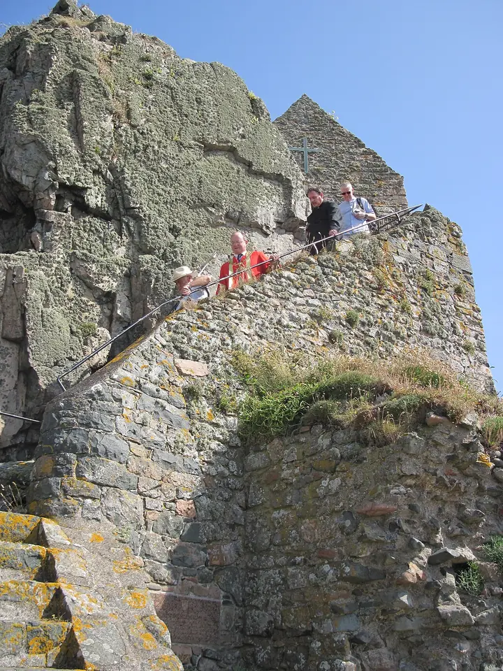 Pilgrims climbing the steep stone steps cut into the Hermitage Rock toward the small chapel at its top