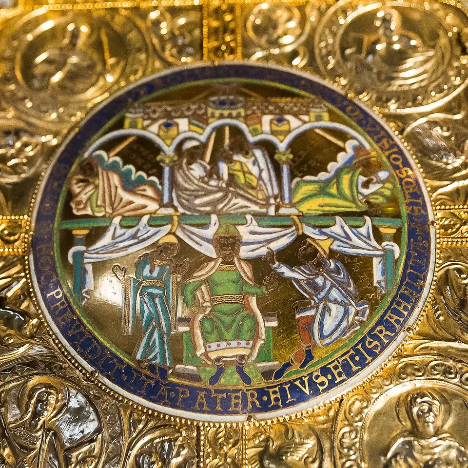 A round medieval enamel ringed by a blue Latin inscription, showing figures asleep under arches above and a crowned man enthroned between two attendants below