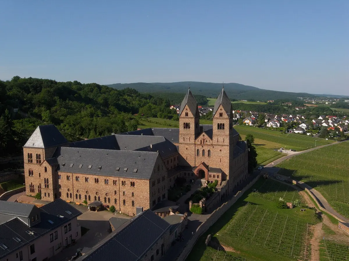 A red sandstone abbey with twin towers on a hillside among vineyards above the Rhine valley