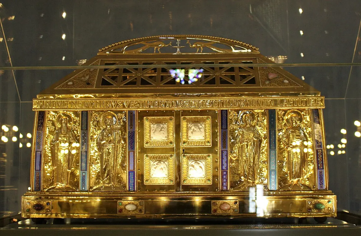 A gilded house-shaped reliquary with figures of saints in arched niches and enameled panels, behind glass