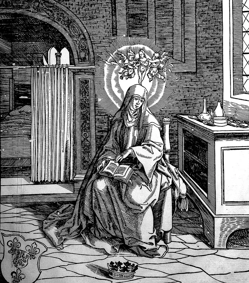 Black-and-white woodcut of a haloed abbess seated in a vaulted room reading a book, with angels in a glory above her head and a crown lying on the floor at her feet