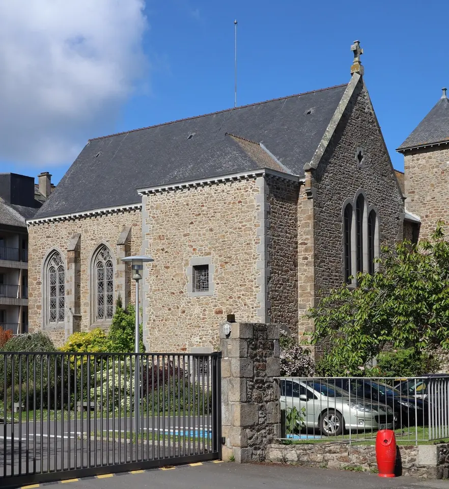 A gray granite chapel with a steep slate roof and tall pointed windows behind an iron gate in Saint-Servan, Brittany