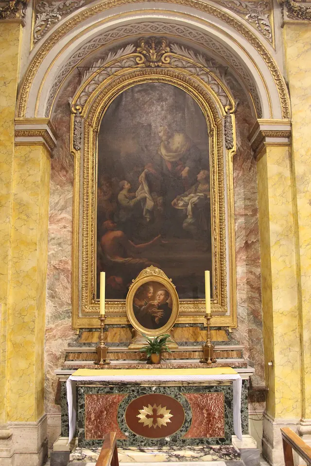 Side altar in a Roman church with a tall arched dark painting of St. John Cantius in a gilded frame, set in yellow and pink marble