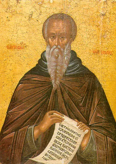 A Russian icon of a balding monk with a long gray beard in a brown habit, holding an unrolled scroll covered in Slavonic writing