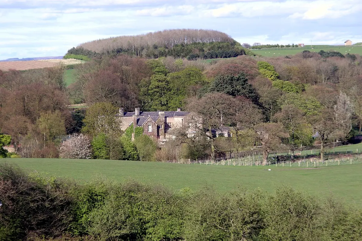 An old stone manor house with mullioned windows among trees and green fields in the Lancashire countryside