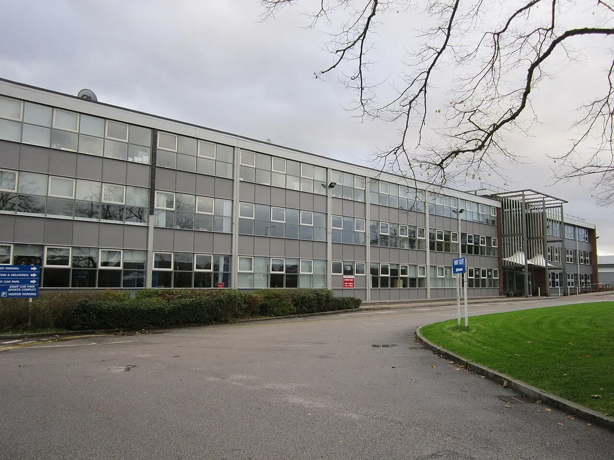 Modern brick buildings of a Catholic sixth-form college named for St. John Rigby, with a lawn in front