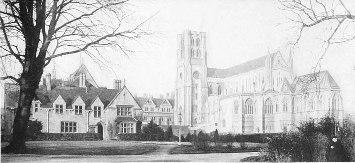 Old black-and-white photograph of a stone monastery house and a tall Gothic abbey church behind bare trees