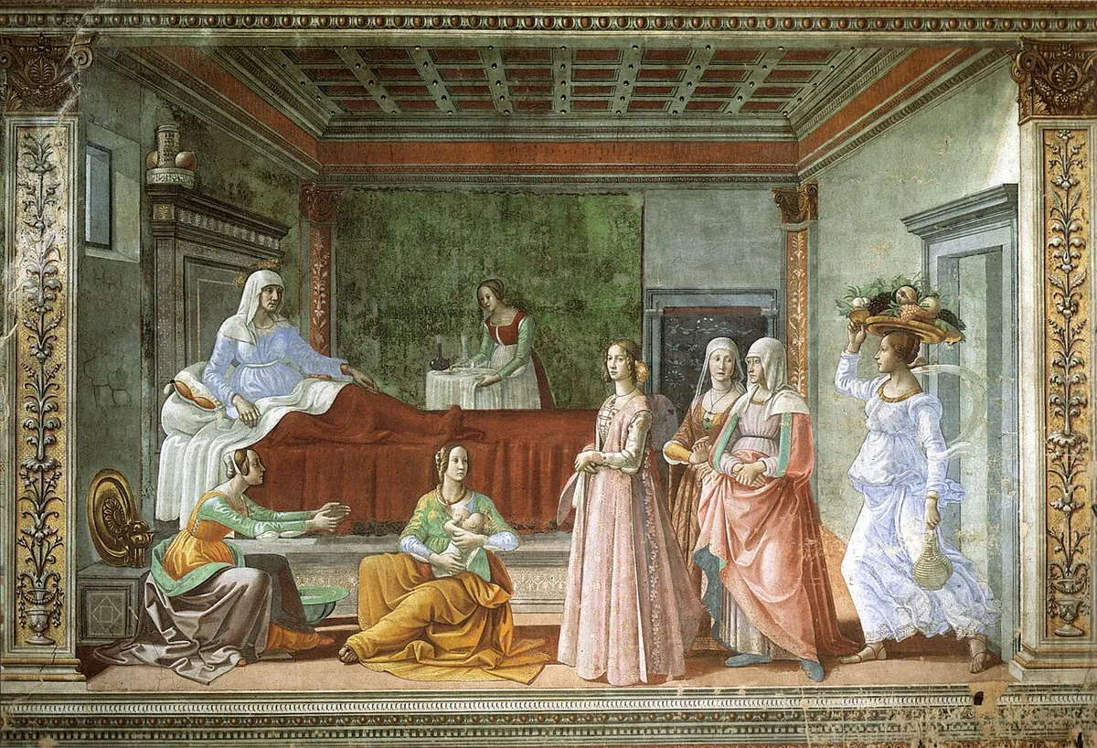 Fresco de una alcoba florentina donde Isabel descansa en la cama mientras unas mujeres atienden al recién nacido Juan y llegan visitantes elegantes, una con fruta sobre la cabeza