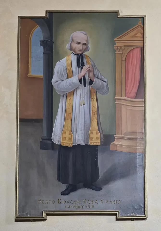 Painting of a thin, white-haired priest in a black cassock, white surplice and gold stole, hands joined in prayer, standing in front of a confessional