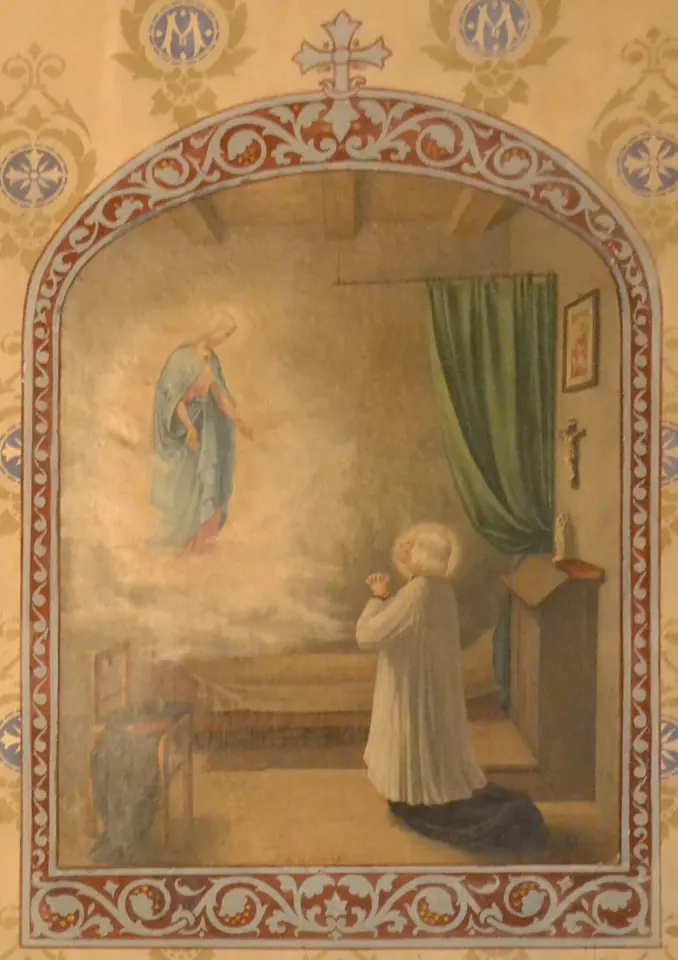 Mural painting of the Curé of Ars kneeling in prayer in his bare room, with a vision of the Virgin Mary in the upper left, in a decorated arched frame